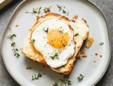 Croque madame sandwich jamón y queso con salsa de queso y huevo estrellado arriba
