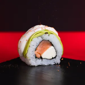 Acevichado Sake Roll Nikkei envuelto en palta con salsa acevichada y shichimi togarashi, relleno de salmón y queso crema. Sakai Sushi Providencia.