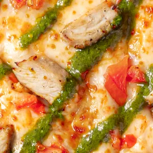 Pizza Pollo Pesto con pollo, pesto, tomate, queso mozzarella y salsa de tomate.