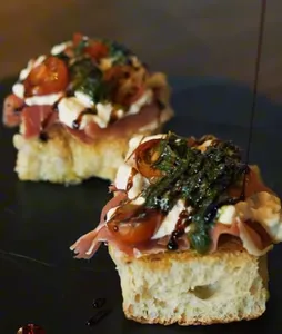 Tostada Caprese Stracciatella de 7 cueros, Tomates Cherry , Pesto de la casa, Prosciutto.