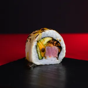 Tropical Nikkei Roll envuelto en queso crema gratinado, topping de salsa de maracuyá, relleno de atún, palta y papa camote en hilos. Sakai Sushi Providencia.